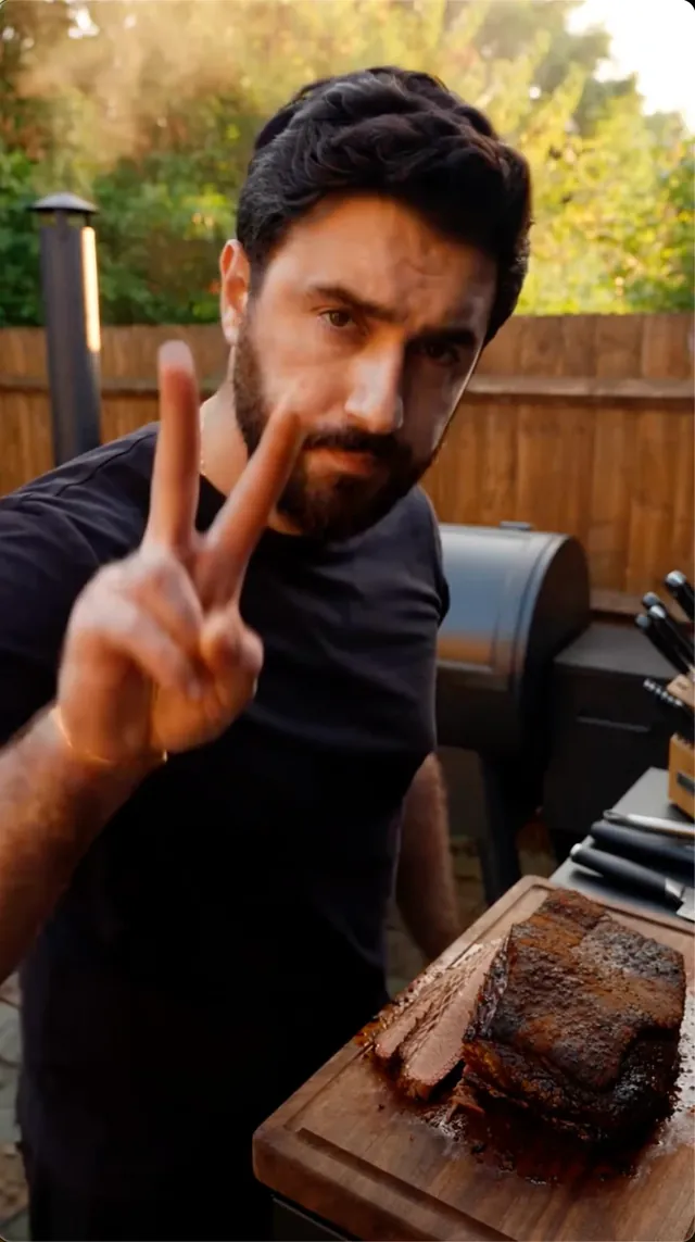 Man giving a peace sign next to a freshly sliced brisket