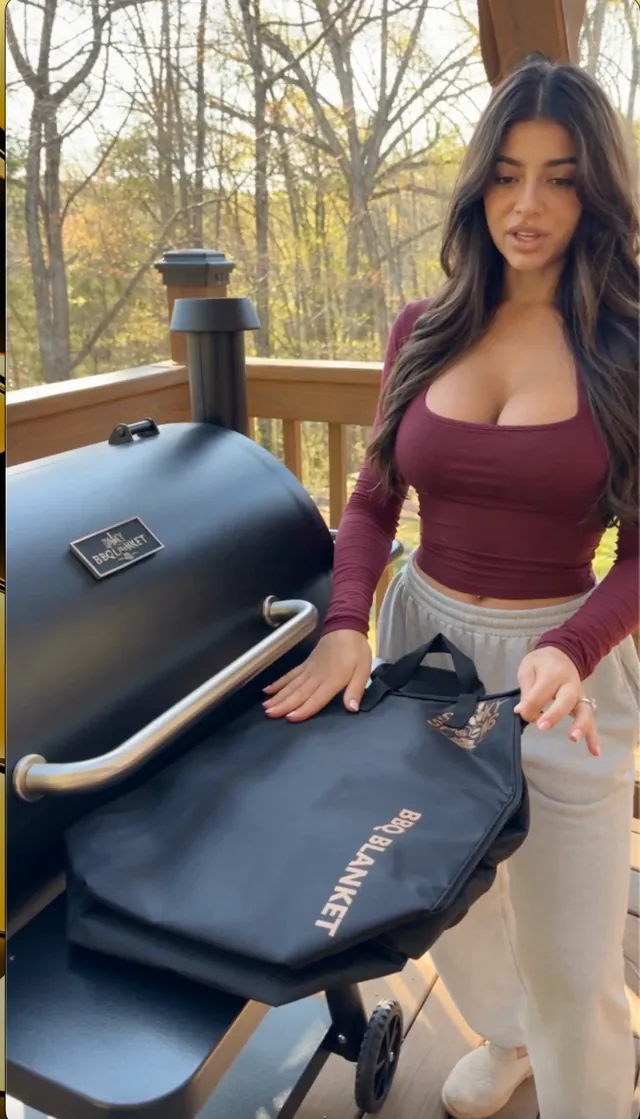Woman placing the Smoky Spoons BBQ Blanket on her pellet smoker